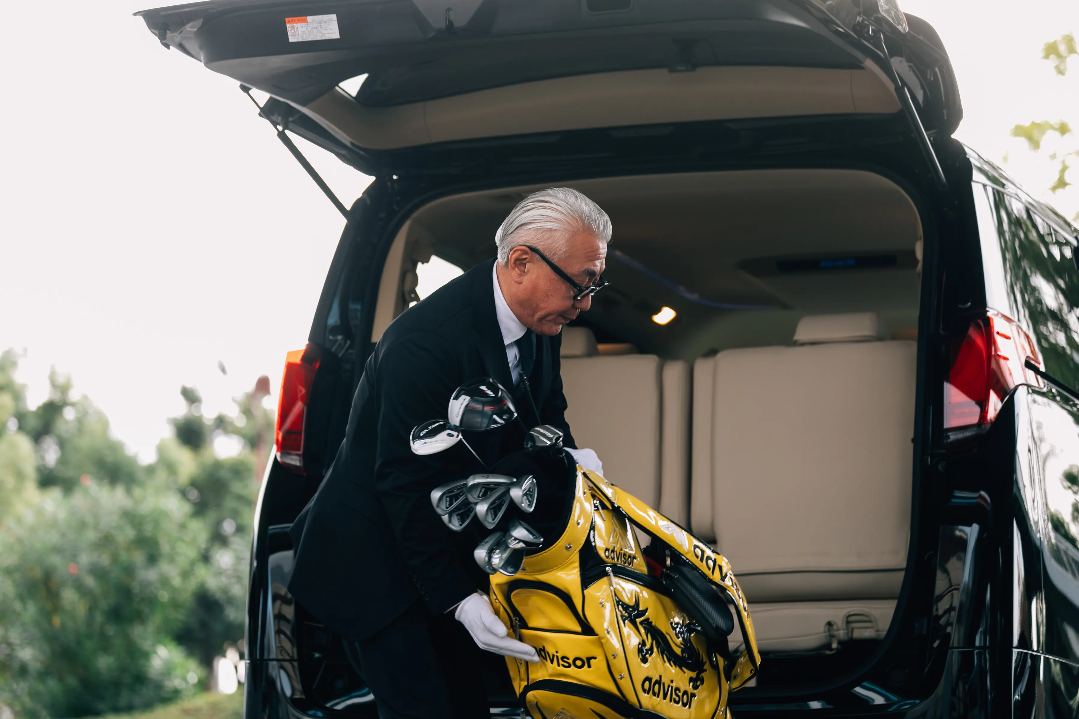 ドライバーがゴルフバッグを積み込む様子